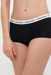 Μαύρο βαμβακερό σλιπάκι με λευκή ελαστική ζώνη που αναγράφει "BJÖRN BORG" σε μαύρα γράμματα. Λείος υφή, σχέδιο hipster.