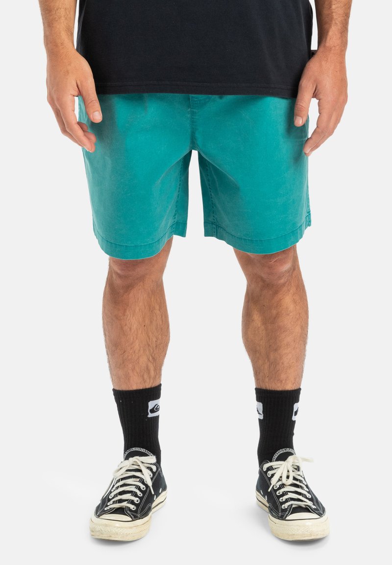 Turkosa shorts i bomull, med en avslappnad passform, platt midja och sidofickor. Kombinerat med svarta strumpor och sneakers.