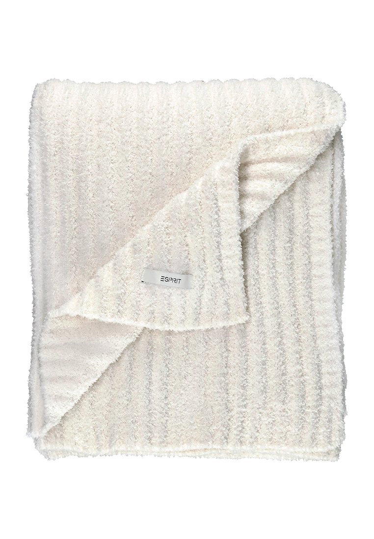Couverture blanche texturée avec un motif en relief, repliée sur elle-même. Une petite étiquette avec le nom de la marque "ESPRIT" est visible.