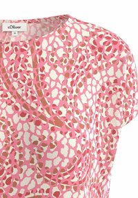 T-shirt à manches courtes en rose avec un motif à pois de accents blancs et beiges. Encolure ronde, tissu doux avec une texture lisse.