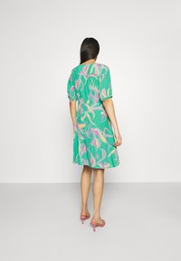 Short-sleeve teal dress featuring a vibrant floral pattern in pink, yellow, and green, with a fitted waist and flowing skirt.