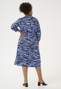 Blauwe en zwarte zebraprint jurk met een getailleerde taille, lange mouwen en een gerimpelde halslijn. Glad materiaal, lengte tot onder de knie en een ontspannen pasvorm.