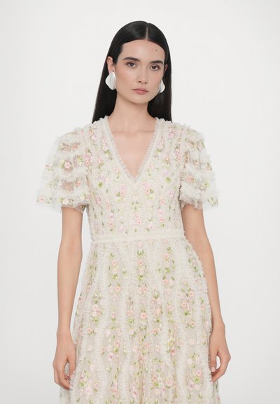 Broderad klänning med V-ringning, korta puffärmar och blommönster i rosa och grönt på krämig bakgrund, tillverkad av genomskinligt material.
