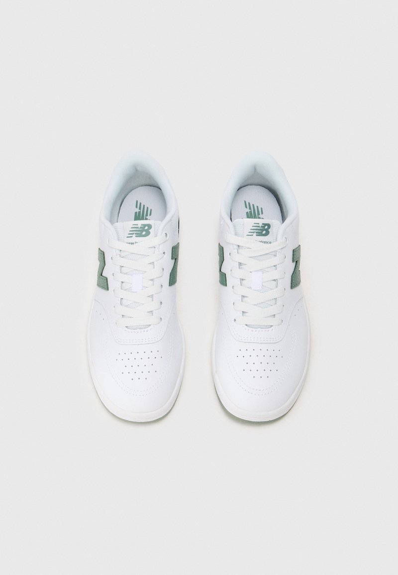 Zapatillas deportivas blancas con acentos verdes y puntera perforada. Cuenta con cordones, cuello acolchado y logo impreso en la lengüeta.