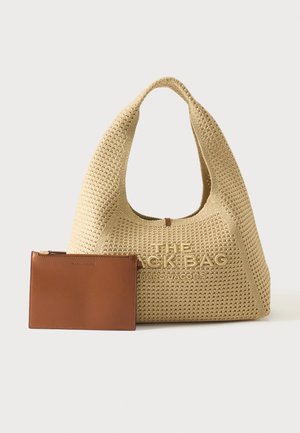 Beżowa, pleciona torebka Marc Jacobs z dużym uchwytem i wytłoczonym nazwiskiem marki, obok małej brązowej skórzanej saszetki na suwak.