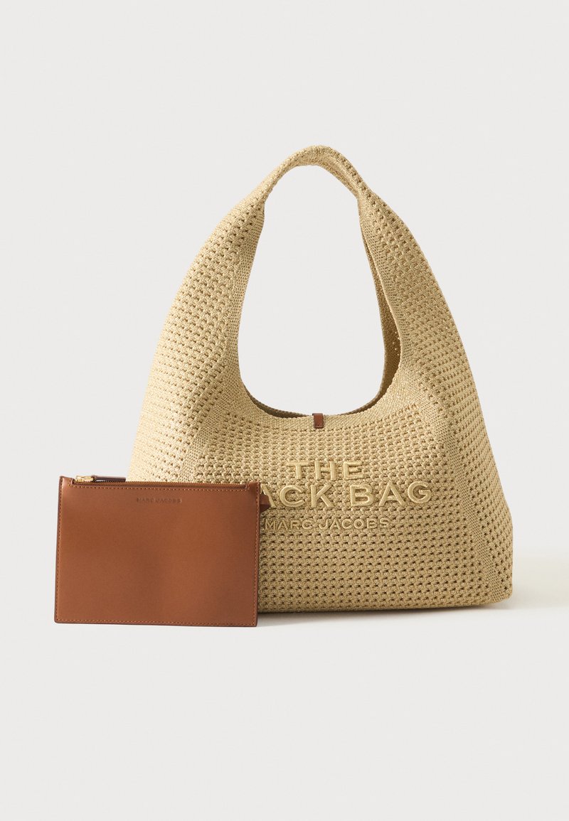 Sac à main tissé beige Marc Jacobs avec grande poignée et nom de marque embossé, à côté d'une petite pochette en cuir marron avec fermeture éclair.