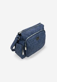 Bolso de hombro de mezclilla azul marino con patrón floral acolchado, compartimentos dobles con cremallera, correa ajustable y detalles de metal en tono plateado.