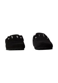 Zuecos de ante negro con punta redondeada, con acentos de costura blanca y una correa trasera, suela de goma texturizada. Diseño sencillo, sin adornos.