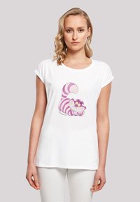 Hvit bomull t-skjorte med et fargerikt grafikk av Cheshire-katten i lilla og rosa striper, med korte ermer og rund halsåpning.