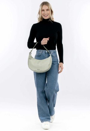 Hobo-Tasche aus hellgrünem, gestepptem Material, mit einer geschwungenen Form und einem Trageriemen; getragen zu einem schwarzen Oberteil und blauen, weiten Jeans.