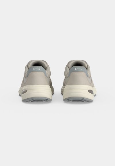 Paire de chaussures de sport gris clair vues de dos avec des semelles blanches épaisses et un tissu en mesh près de la cheville.