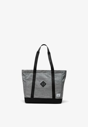 Bolso tote gris y negro con asas largas negras, parche delantero en forma de diamante y pequeña etiqueta de marca blanca en la esquina inferior derecha.