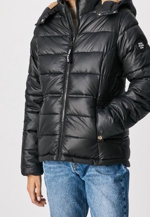 Chaqueta acolchada negra con cremallera frontal, diseño de acolchado horizontal, capucha color beige y parche de logo en la manga. Tejido suave y brillante con bolsillos.