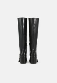 Botas de cuero negro hasta la rodilla con una textura suave, que cuentan con un tacón grueso y un detalle de cremallera en el lado interno.