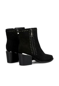 Botines negros de ante con cremallera lateral, detalles con tachuelas y un tacón grueso negro. La punta es afilada, lo que realza el diseño elegante.