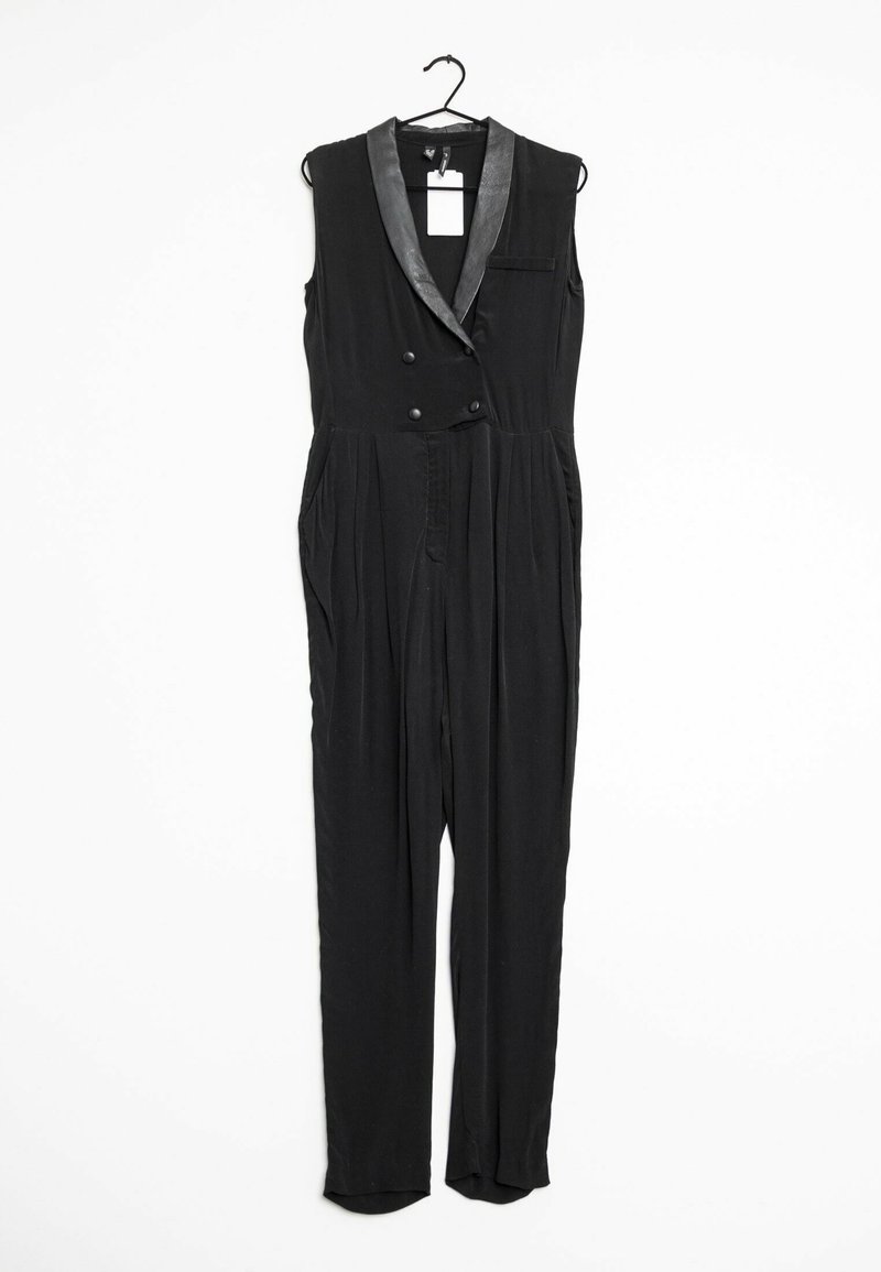 Black sleeveless jumpsuit with a satin-like collar, double-breasted buttons, side pockets, and tapered legs. Hangs on a black hook.