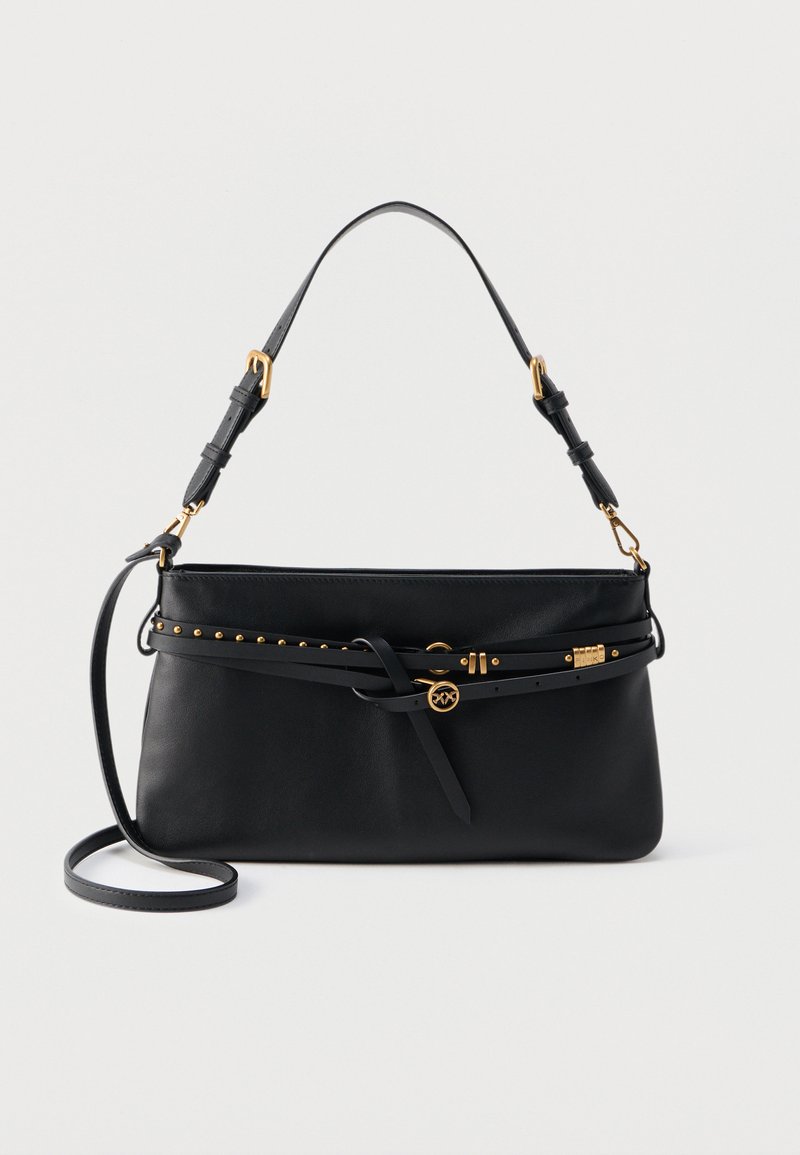 Μαύρη δερμάτινη τσάντα ώμου με ρυθμιζόμενο λουράκι, διακοσμητική λεπτή ζώνη με χρυσά καρφιά και στρογγυλό χρυσό μενταγιόν με το λογότυπο.