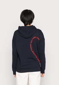Granatowy bluza z kapturem, z dużym czerwonym logo oplatającym tył, z kapturem na sznurku oraz prążkowanymi mankietami i dołem.