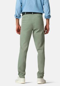 Groene katoenen broeken met een slim fit, voorzien van twee achterzakken, een soepele textuur en opgerolde mouwen, gecombineerd met witte sneakers.