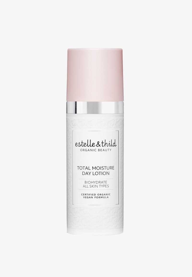 Botella cilíndrica blanca con superficie texturada, tapón mate rosa y acento plateado. La etiqueta muestra prominentemente "Loción Hidratante Total para el Día".