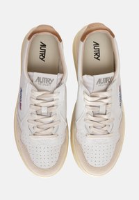 Sneakers bianchi in pelle con accenti in suede beige, punta rotonda, dettagli perforati e lacci beige. Presenta il logo sulla linguetta e sul lato.