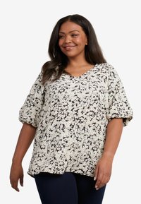 Blusa a maniche corte color crema con stampa floreale nera. Design con scollo a V, vestibilità rilassata e maniche arricciate. Tessuto morbido e leggero.