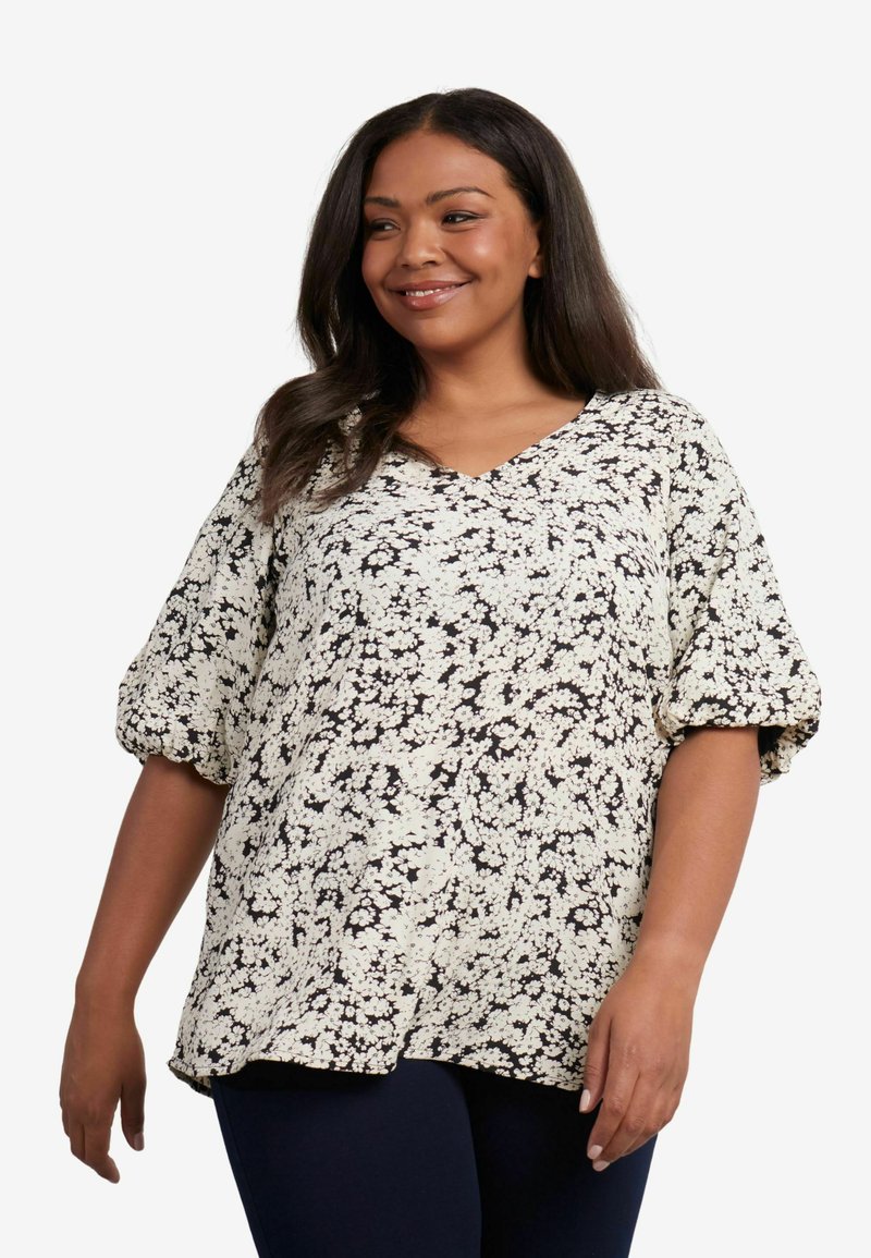 Blusa a maniche corte color crema con stampa floreale nera. Design con scollo a V, vestibilità rilassata e maniche arricciate. Tessuto morbido e leggero.