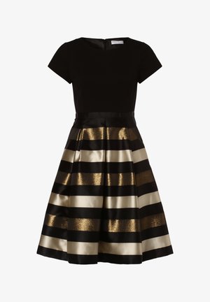 Abito nero con maniche corte e un corpino aderente. La gonna presenta righe alternate di nero lucido e oro metallico. Chiusura con zip sul retro.
