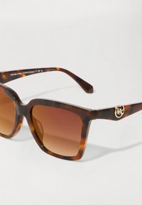 Ochelari de soare din plastic cu model tartău, lentile bordeaux cu gradient, ramă pătrată și un logo auriu MK pe bradă. Suprafață texturată și finisaj neted.