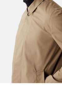 Beige Mantel mit Kragen und einem Knopf. Hat eine glatte Textur und Seitentaschen, präsentiert vor einem neutralen Hintergrund.