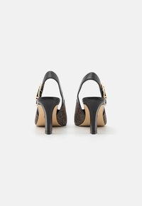 Zapatos de tacón slingback de cuero negro con un patrón marrón texturizado en los laterales, detalles en dorado y tacones medianos de bloque.