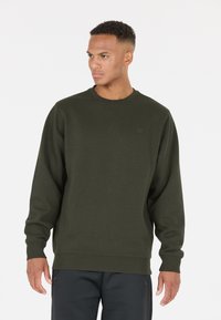 Sweatshirt vert olive à manches longues et col rond. Fabriqué en mélange de coton doux, avec des poignets et un ourlet côtelés, détail de logo minimaliste.
