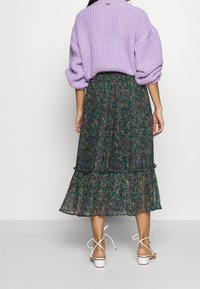 Lila, ylipitkä neulepaita, jossa on pudotetut olkapäät; kerroksellinen, hulmuava musta hame, jossa on värikkäitä kukkakuoseja; valkoiset remmipohjalliset kengät.