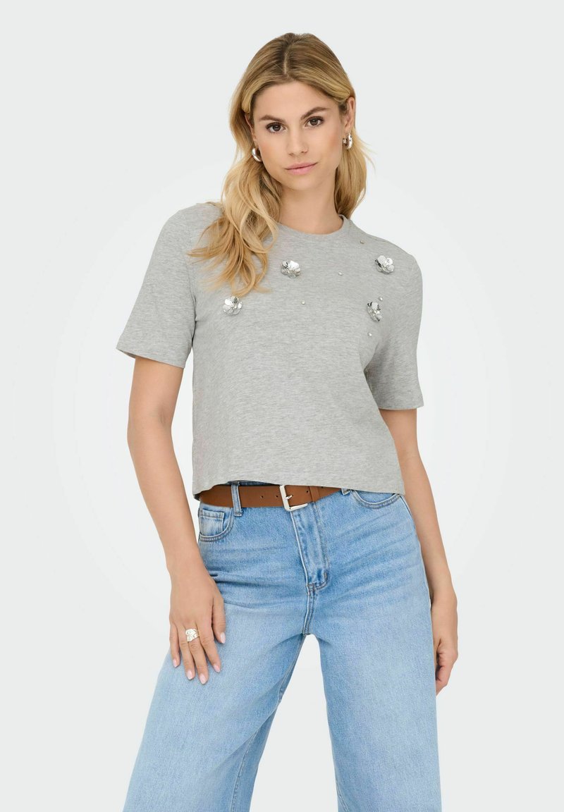 T-shirt grigio corto con maniche corte, decorato con fiori e piccoli gemelli. Abbinato a jeans azzurri a vita alta.
