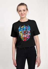 Sort t-shirt med farverigt grafik af Power Rangers i et cirkulært design, med blå, rød, pink, gul og sorte accenter.