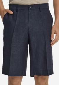 Mörk marinblå linneshorts med platt front, två sidofickor och en knappstängning framtill. Rakt avslut med lätt textur.