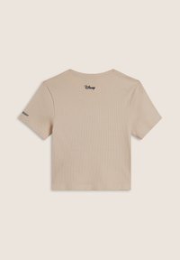 T-shirt beige à manches courtes côtelé avec un logo "Disney" en noir au dos et un accent sur la manche gauche. Matière en coton douce.