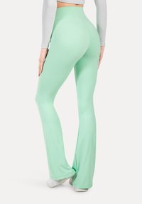 Leggings a campana verde menta realizzati in tessuto elastico e liscio con un design a vita alta; presentano una vestibilità sartoriale che esalta la silhouette.