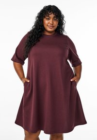 Maroon short-sleeve dress made of soft fabric, featuring a relaxed fit, round neckline, and side pockets at the hem.