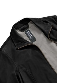 Giacca in pelle nera con chiusura a zip, colletto rialzato e rivestimento crema. Include un'etichetta con dettagli del marchio e della taglia.