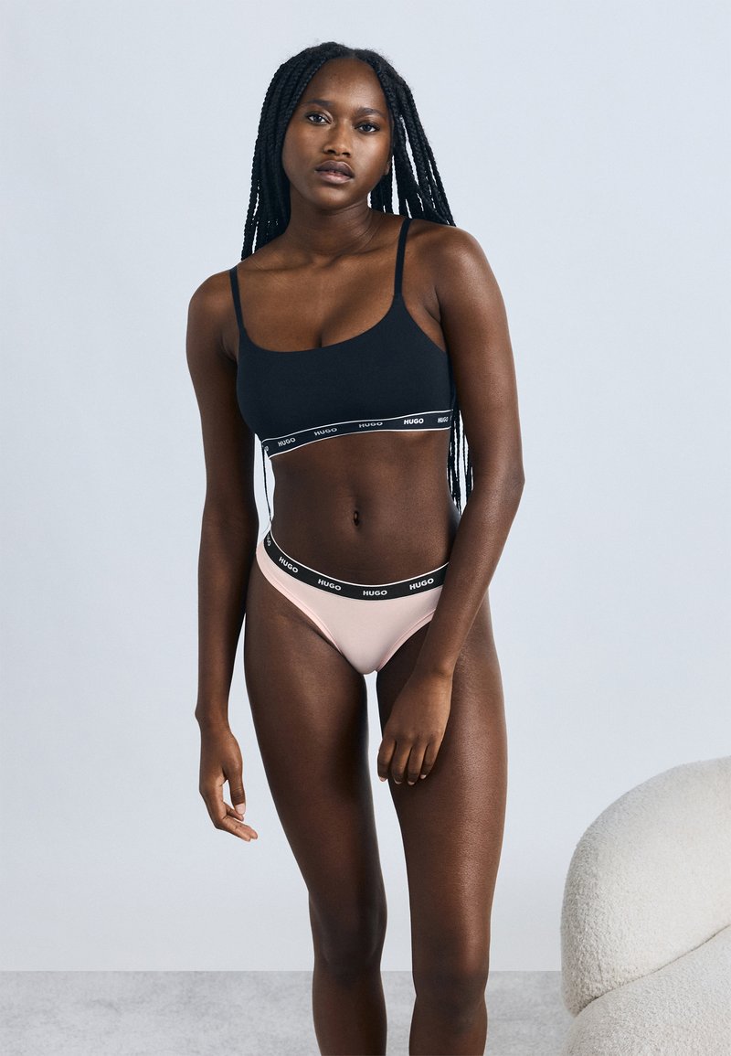 Zwarte bralette met HUGO-logo band, gecombineerd met lichtroze slipje met bijpassende logoband. Soepele textuur en aansluitend model.