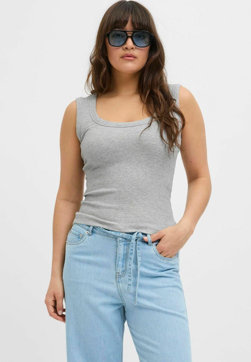 Top a maniche corte grigio a costine con scollatura a barca, abbinato a jeans azzurri a vita alta con fascia legata e una vestibilità comoda.