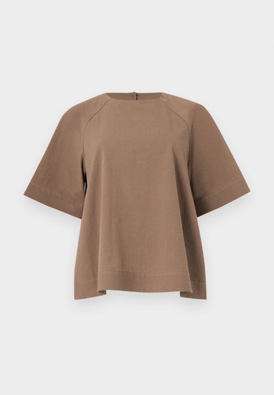 Καφέ κοντομάνικη μπλούζα με άνετη εφαρμογή, φαρδιά μανίκια και στρογγυλή λαιμόκοψη, εκτεθειμένη επίπεδα στο φωτεινό φόντο.
