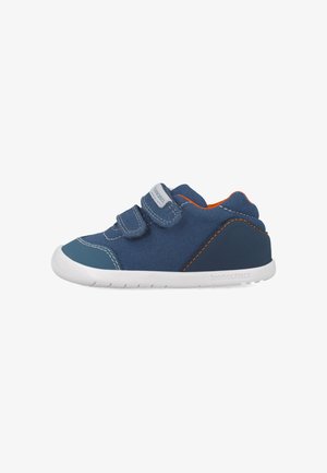 Zapatillas de tela azules con correas de Velcro, suelas de goma y acentos naranjas. Presentan detalles de costura y un logotipo en el lateral.