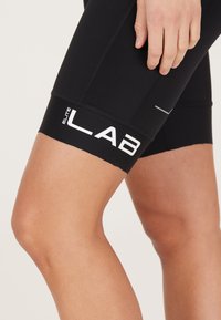 Zwarte sportshorts gemaakt van glad materiaal, met een strakke pasvorm, contrasterende witte branding "ELITE LAB" op de zoom en vlakke naden.