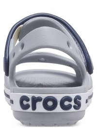 Grå og marineblå Crocs sandal med en rygstrop. Har ventilationshuller og en hvid stribe med "croc" logo. Tekstureret indersål.