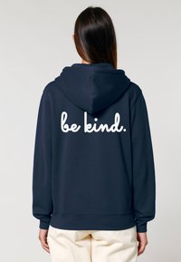 Felpa navy con scritta bianca in corsivo "be kind." sul retro. Realizzata in tessuto morbido, con vestibilità comoda e cappuccio regolabile.