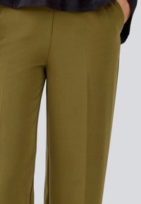Olive green trousers with a smooth texture, featuring a flat front, side pockets, and a relaxed fit, designed for comfort and versatility.