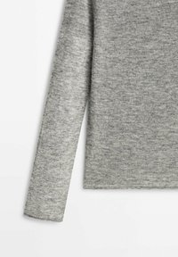 Bras et côté d'un pull gris chiné à manches longues sur un fond blanc, montrant la texture douce du tissu en maille.