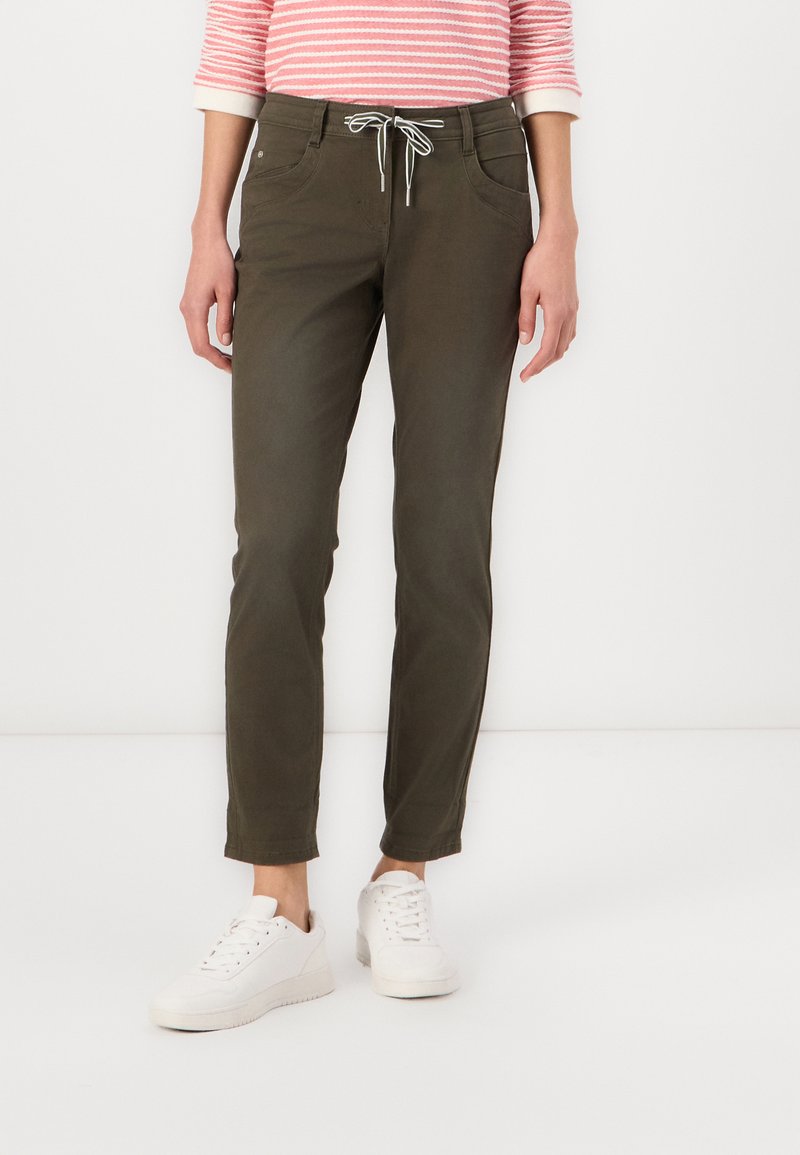 Olivengrønne bukser med snor i taljen, forlommer og smalle ben. Sættes sammen med hvide sneakers, sat mod en enkel hvid baggrund.